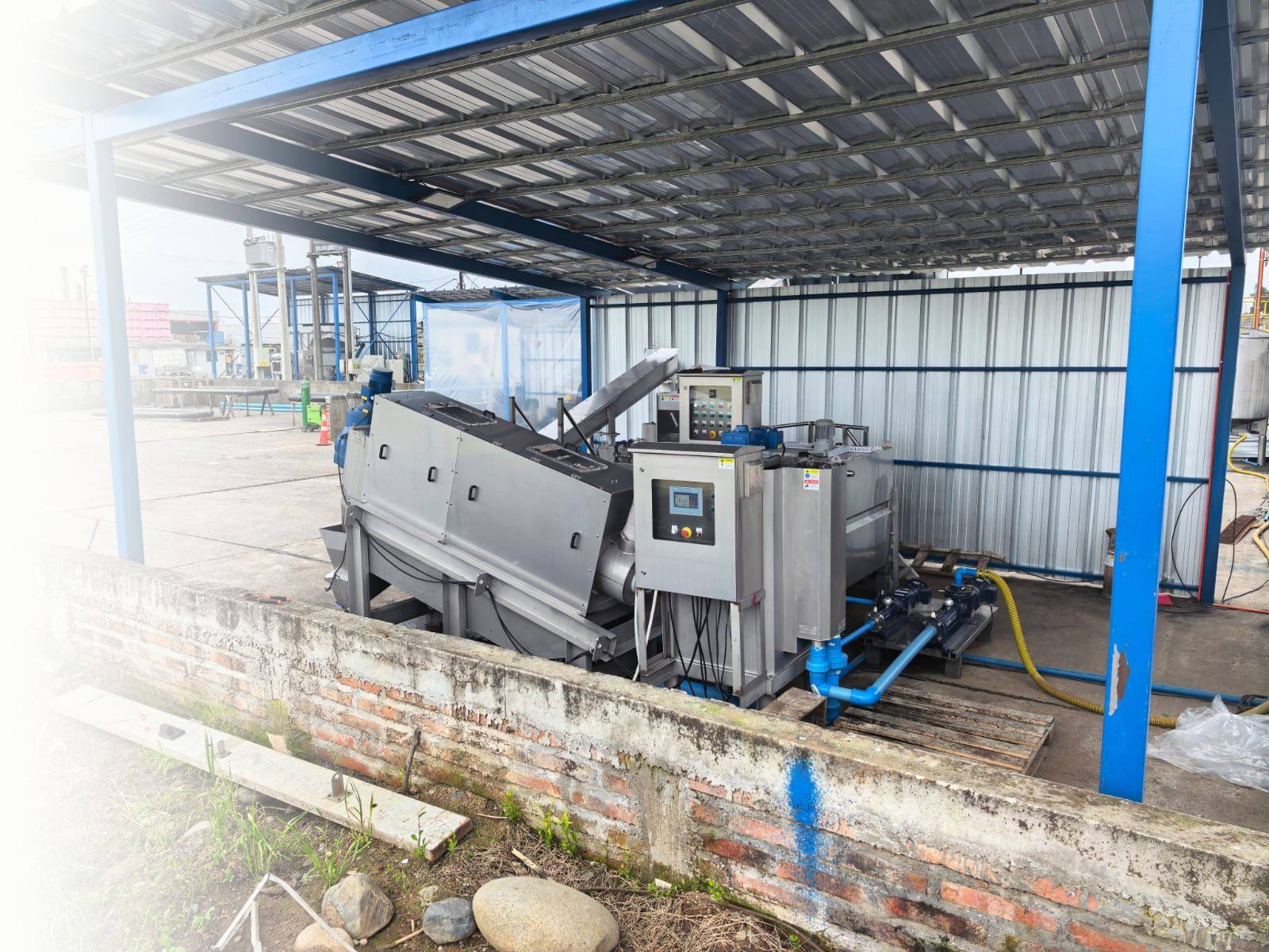Prensa multidisco de acero inoxidable con tablero de control y bombas de alimentación bajo techo